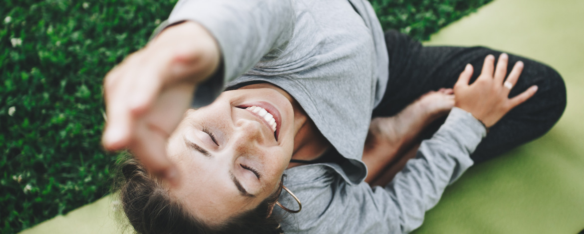 Cheerful and happiness young woman practicing yoga on the green lawn outdoors. Calmness and relax, female happiness