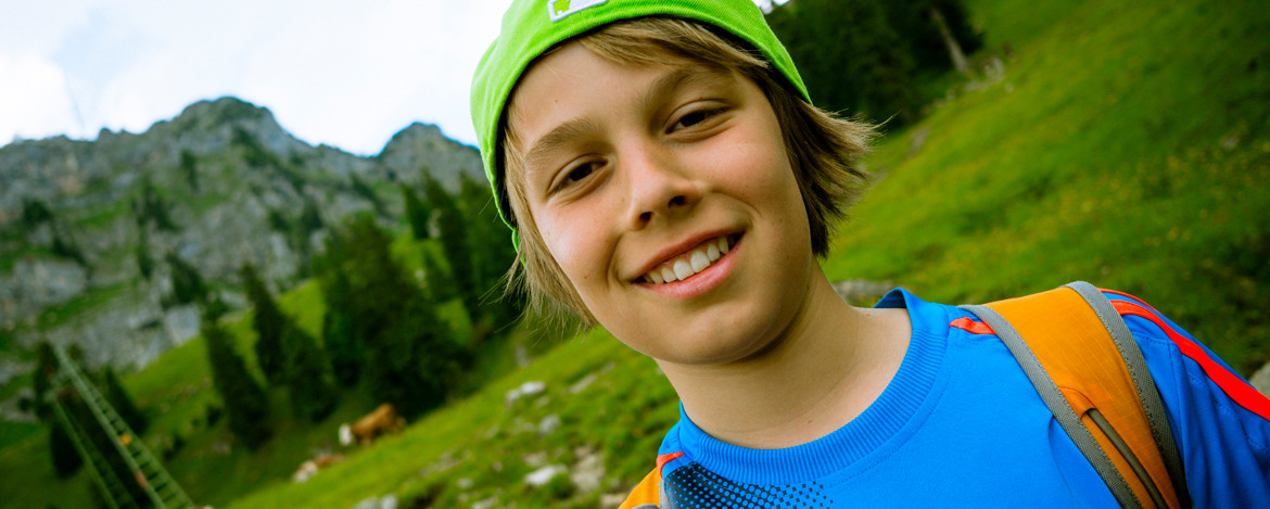 Ein Junge steht lächelnd auf einer Wiese
