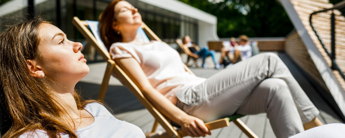 Junge Frauen liegen in Liegestühlen und genießen die Sonnenstrahlen