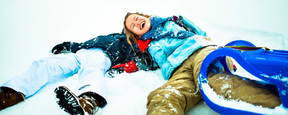 Lachende Kinder liegen im Schnee in Bad Tölz
